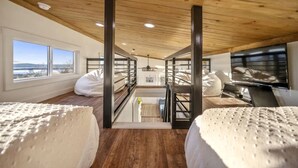 Ein Schlafzimmer im Loft-Stil mit Etagenbetten, einem Fernseher und Blick ins Freie.