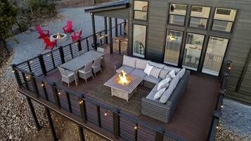 A deck with outdoor furniture, a fire pit, and a modern building with large windows.