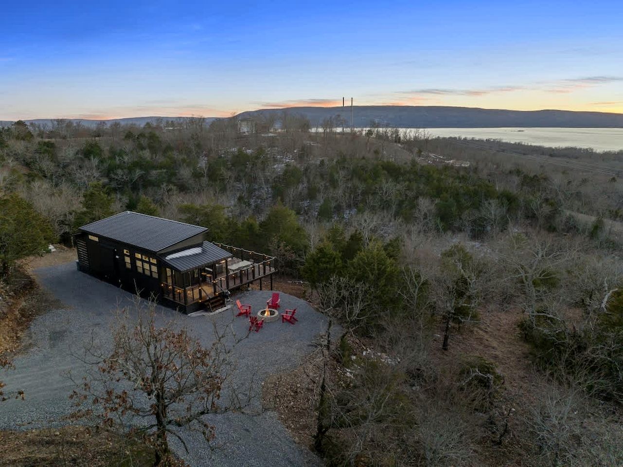 A cabin with a deck, outdoor seating, and a fire pit.