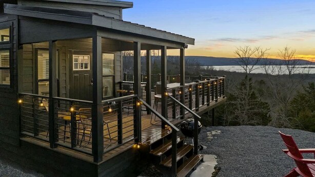 Ein modernes Haus mit Terrasse, Sitzgelegenheit im Freien und Blick auf die Landschaft.