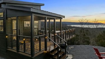 A modern house with a deck, outdoor seating, and a view of the landscape.