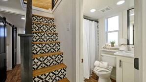 Eine Treppe mit geometrisch gemusterten Wänden, einer weißen Toilette und einem Fenster in einem Badezimmer.