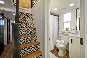 A staircase with geometric patterned walls, a white toilet, and a window in a bathroom. - Serene Tiny Home Retreat with Sunrise Lake & Mountain Views in Pushmataha County, Oklahoma (Pushmataha County)