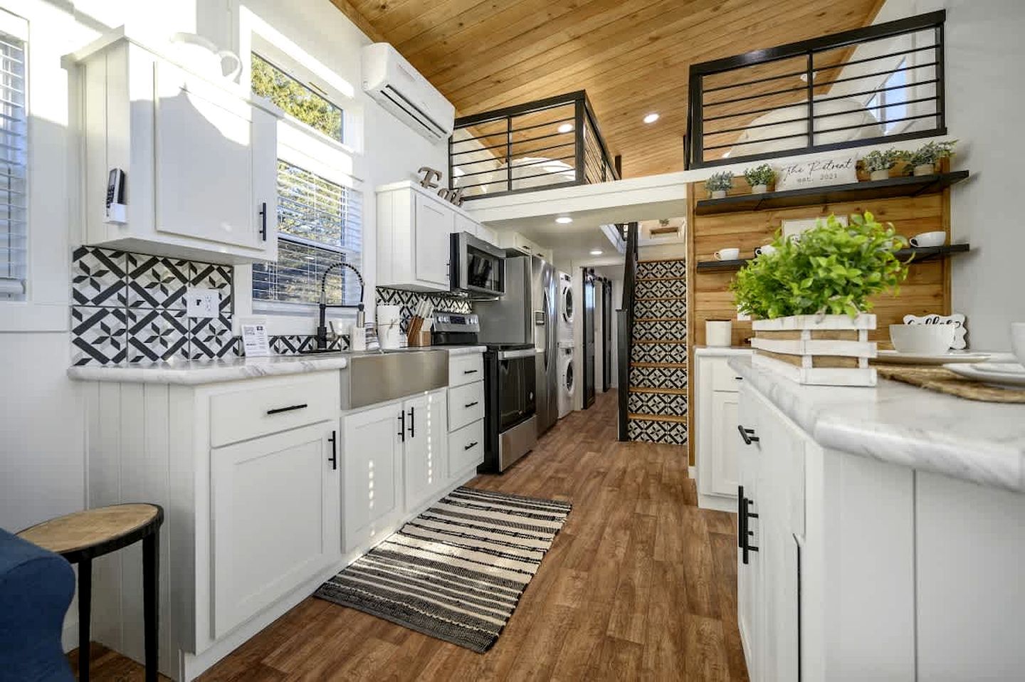 Una cocina moderna con armarios blancos, techo de madera y salpicadero con diseño.