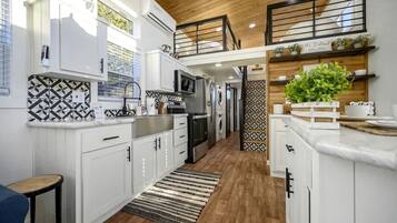 Una cocina moderna con armarios blancos, techo de madera y salpicadero con diseño.