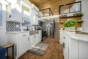 A modern kitchen with white cabinetry, a wooden ceiling, and a patterned backsplash.