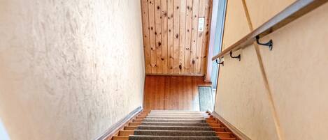 Un escalier avec des marches en bois menant à un palier doté d’un mur en bois.