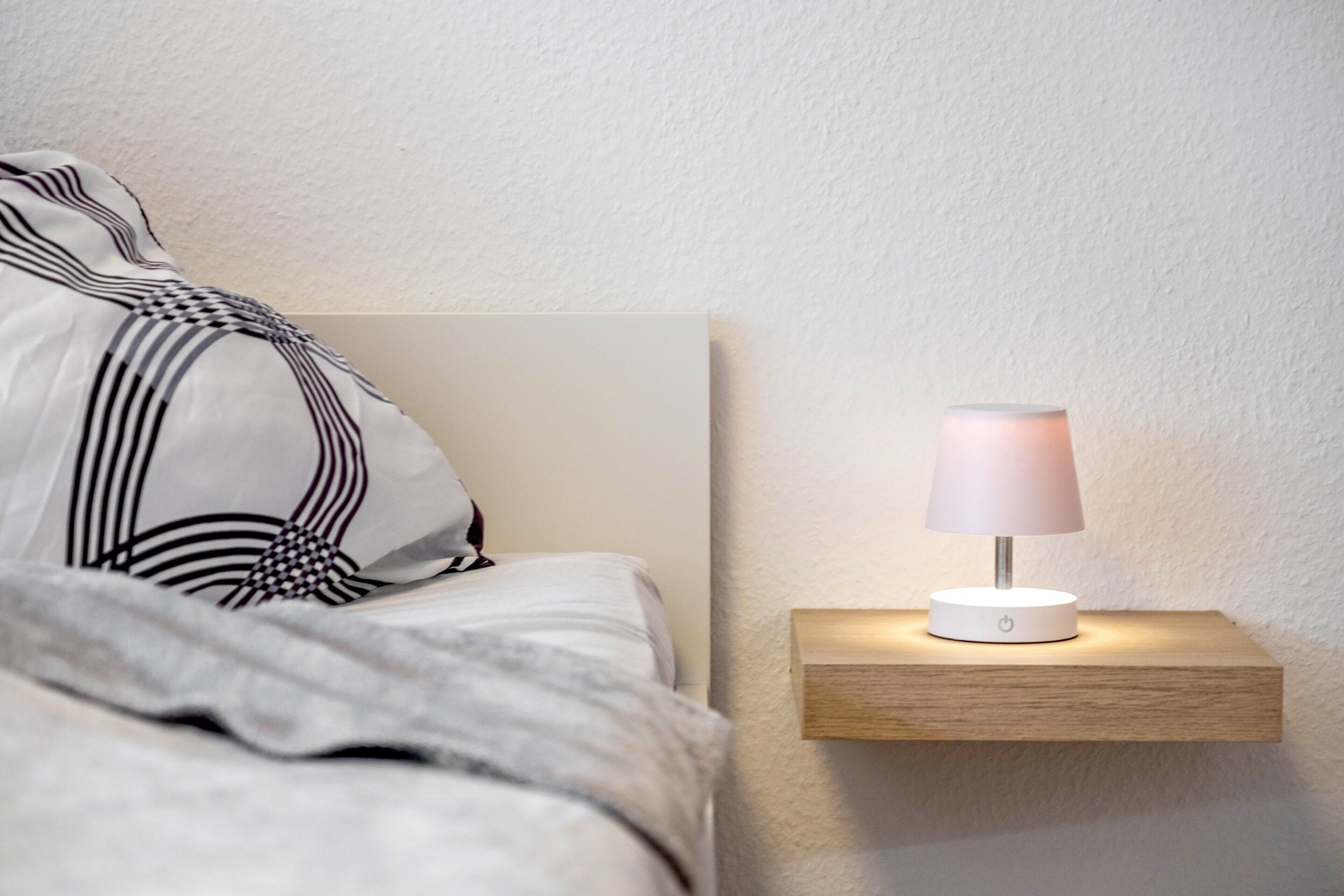 Un lit avec un oreiller à motifs et une table de chevet avec une lampe.