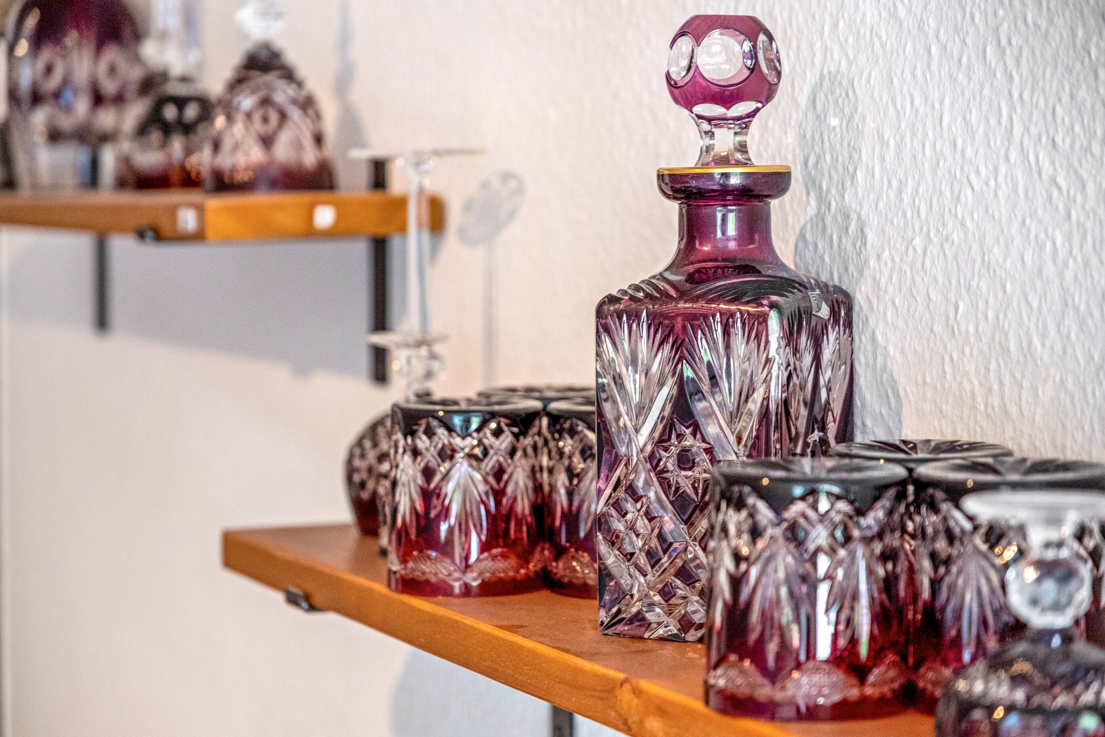 A collection of glass decanters on a wooden shelf.