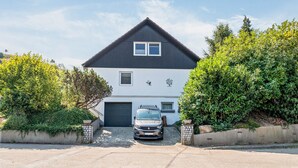 A two-story house with a car parked in the driveway.