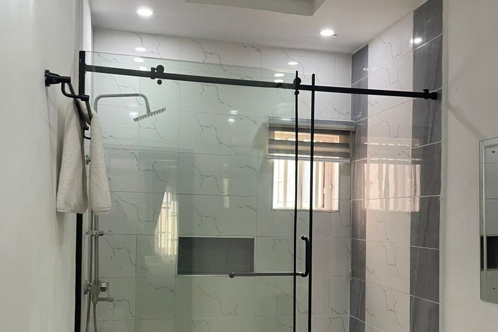 Une salle de bain moderne avec une douche à parois de verre, un porte-serviettes et une fenêtre avec des rideaux.