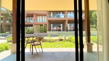 Un edificio moderno con amplios ventanales, un patio con mesa y sillas, y vistas al entorno verde.