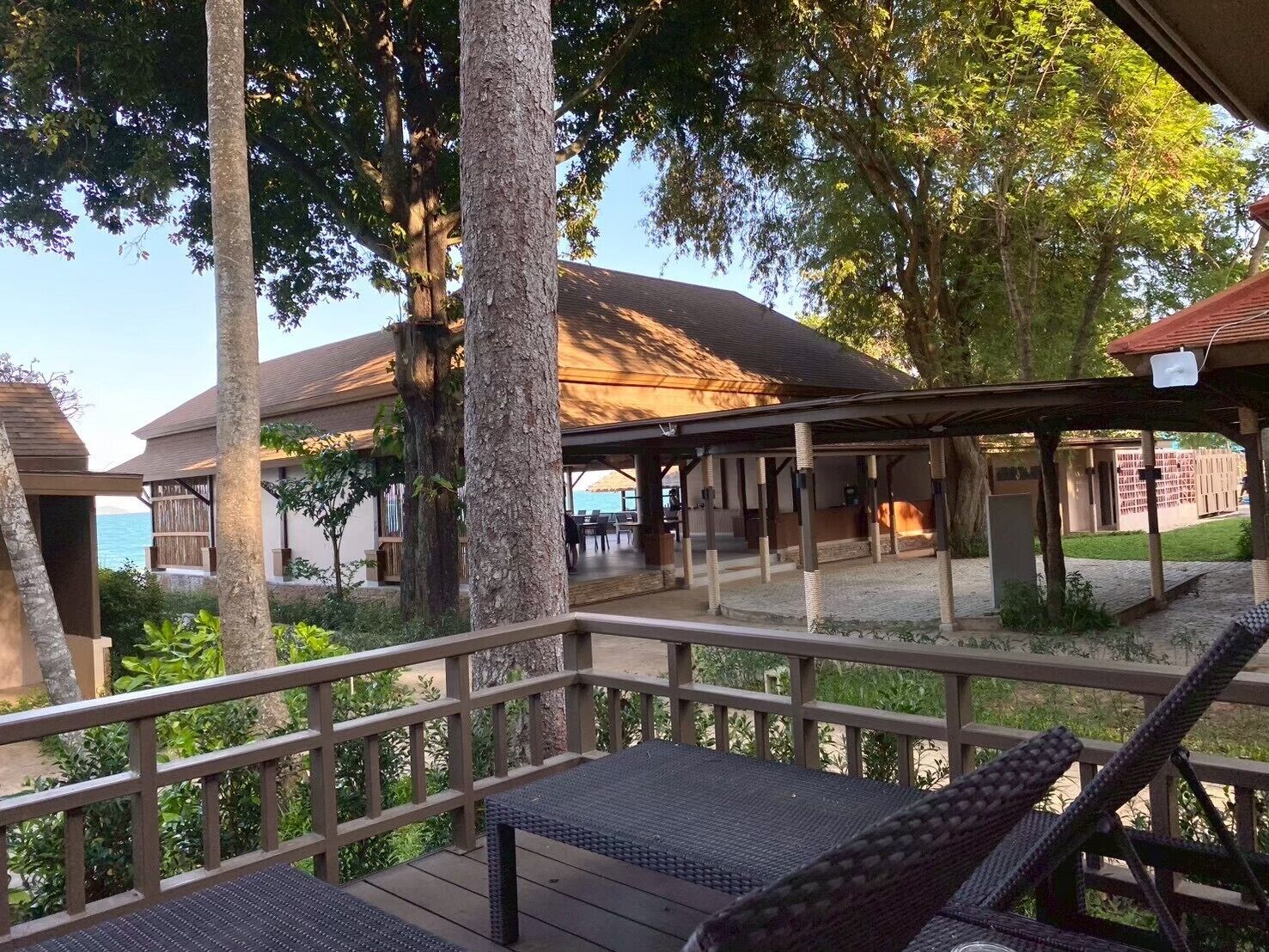 Un espacio de estar al aire libre cubierto, con vista a un edificio y árboles.