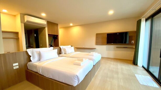 Habitación de hotel con una cama grande, un televisor y puerta corrediza a un balcón.