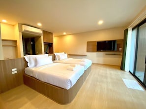 Habitación de hotel con una cama grande, un televisor y puerta corrediza a un balcón.