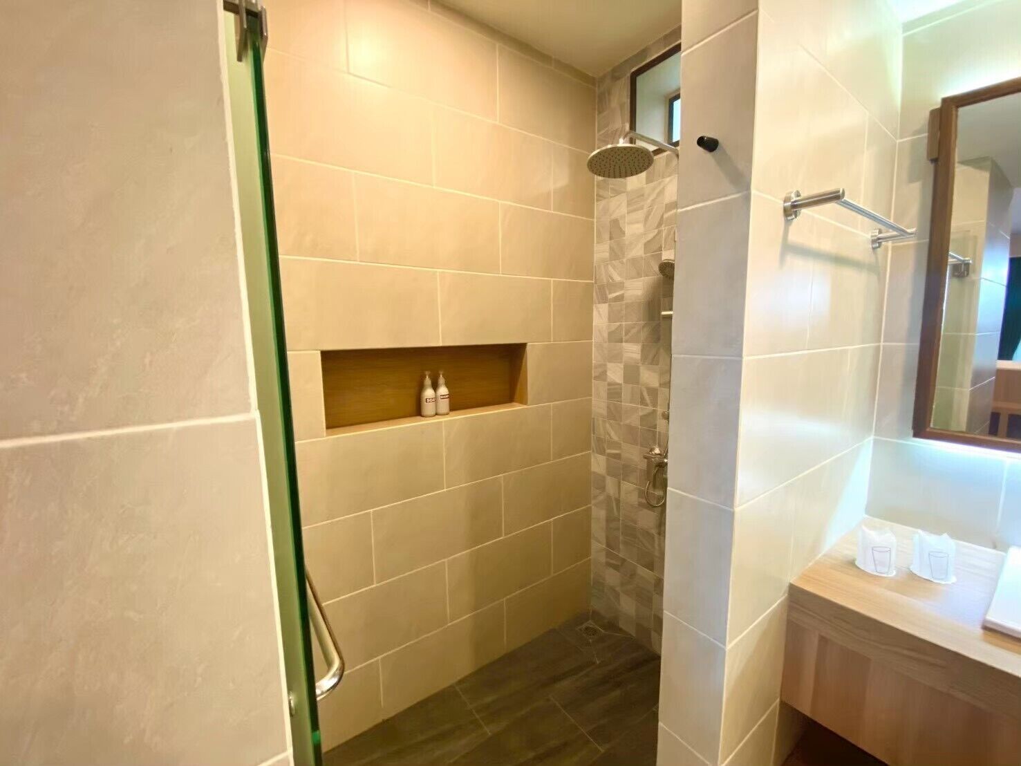 Une salle de bain avec une douche, un meuble-lavabo avec un miroir et une étagère avec des articles de toilette.