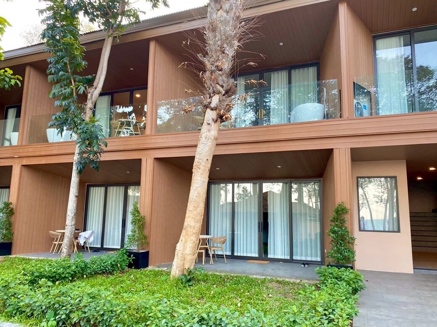 A modern building with multiple balconies, large windows, and a well-maintained garden area.