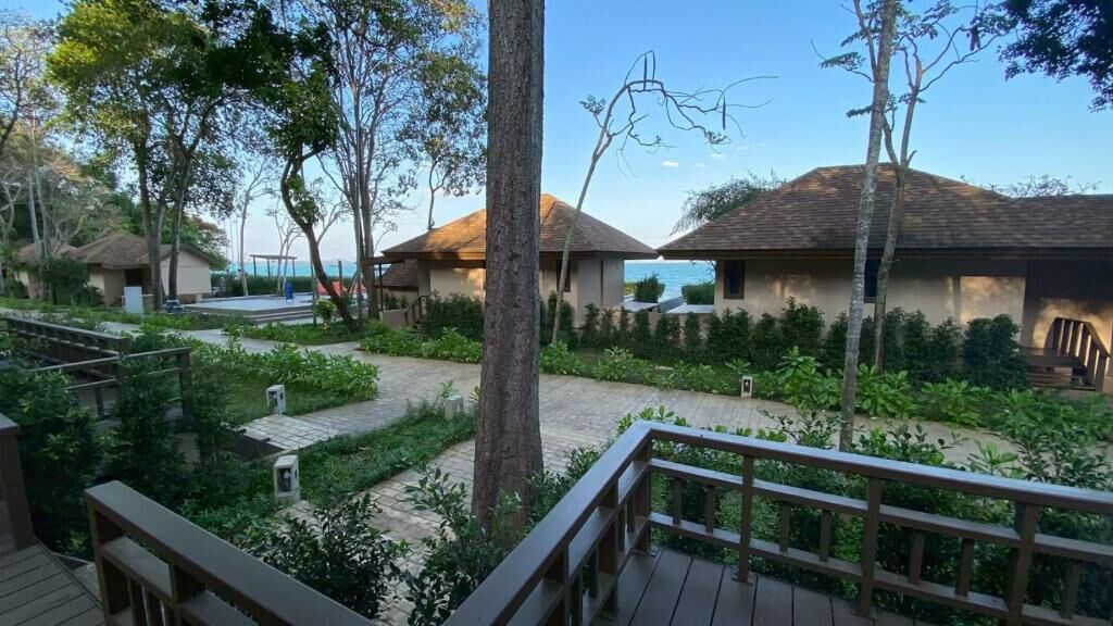 Un resort con cabañas de techo de paja, una terraza de madera y vista al mar.