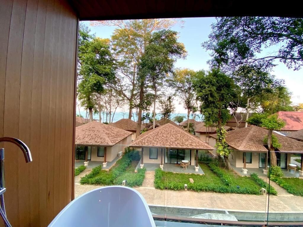 Vista de un hotel con varias habitaciones, cada una con tejado de tejas y rodeada de vegetación.