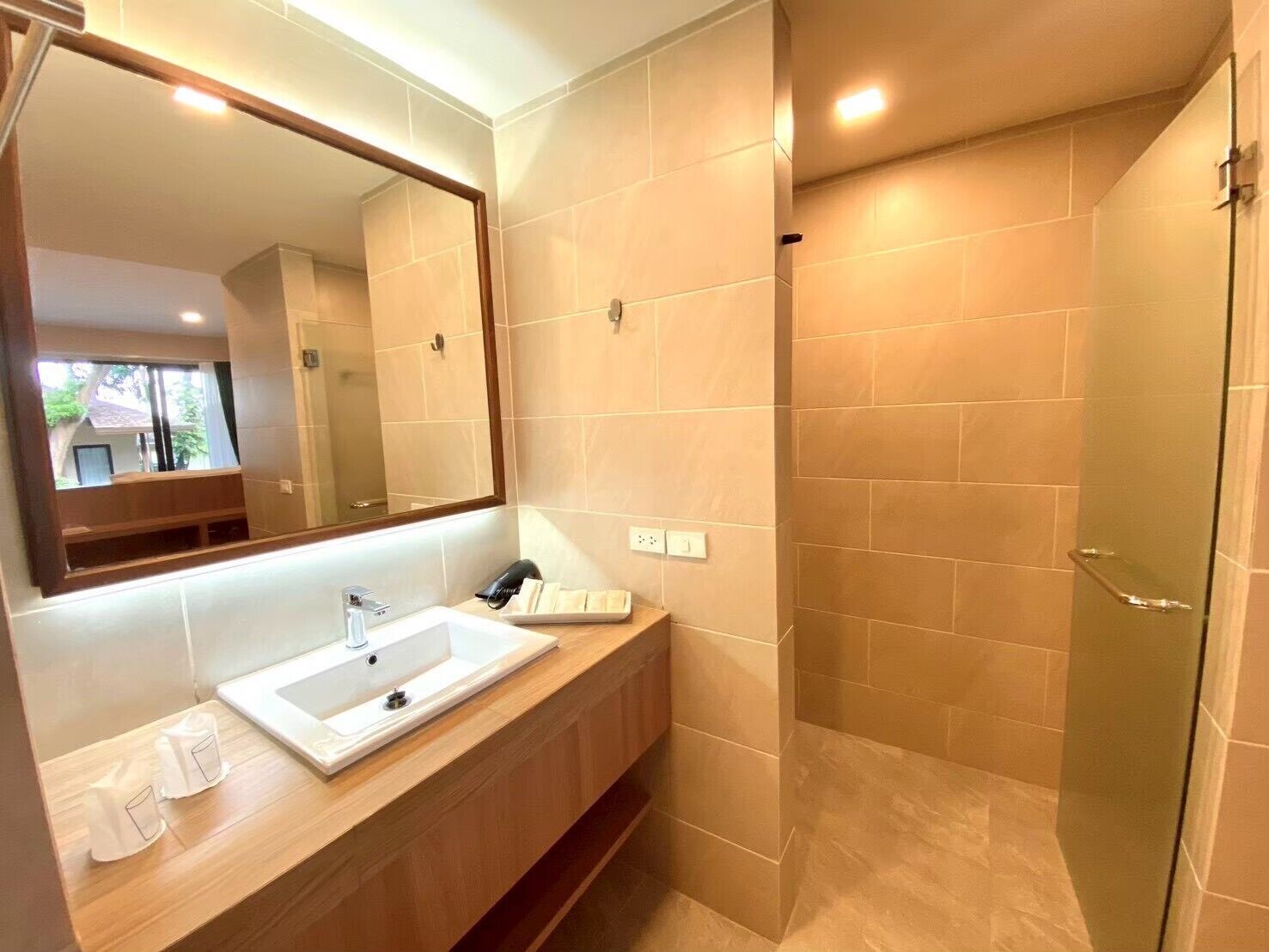 A bathroom with a large mirror, a sink, and a shower area.