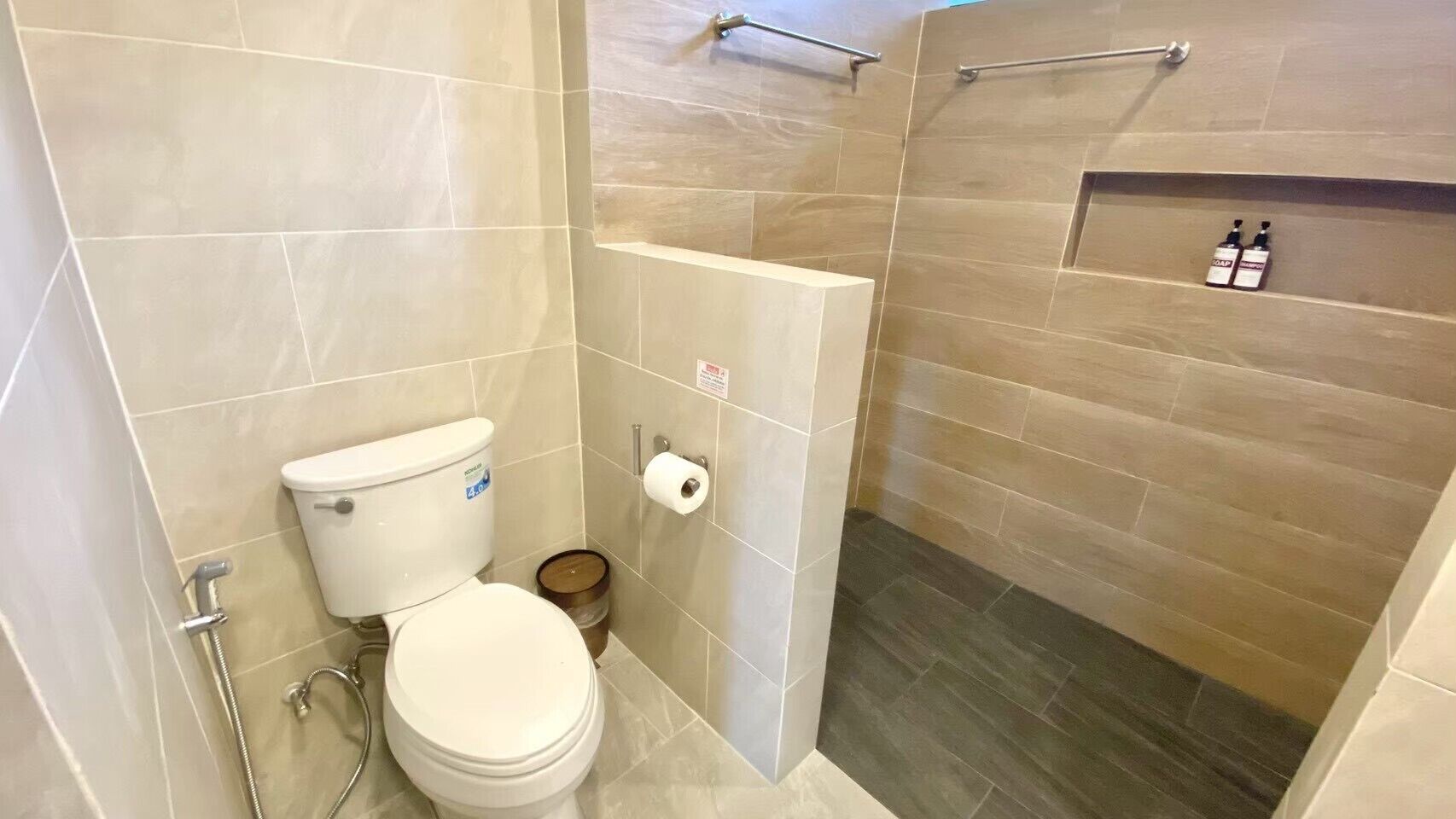 Un baño con inodoro, ducha y un estante con artículos de aseo.