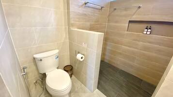 Un baño con inodoro, ducha y un estante con artículos de aseo.