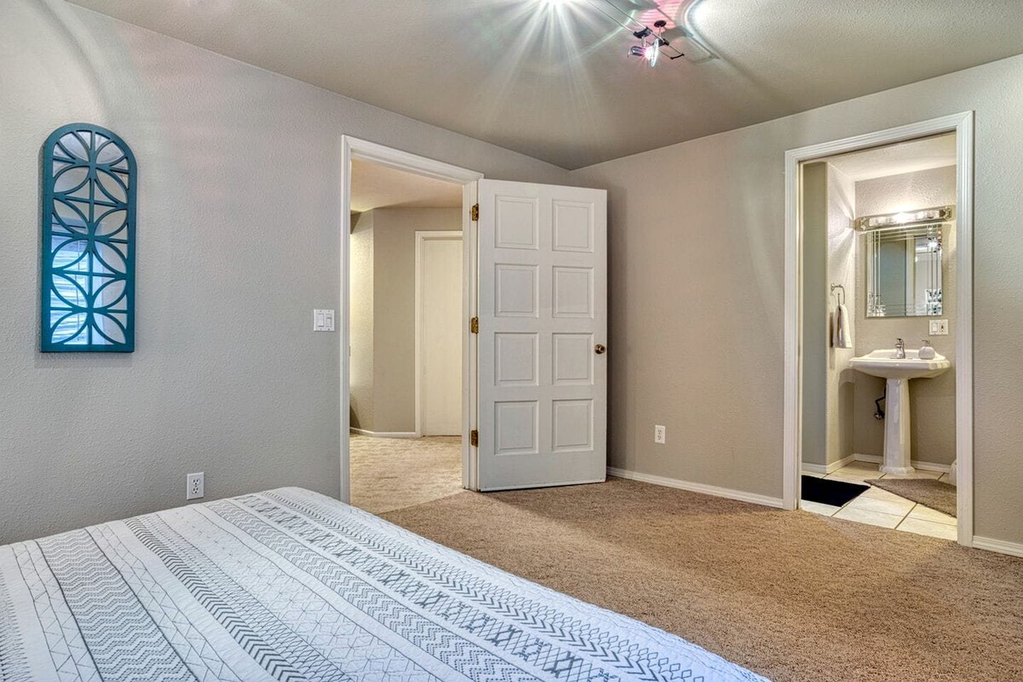 A bedroom with a bed, a door leading to a bathroom, and a hallway.