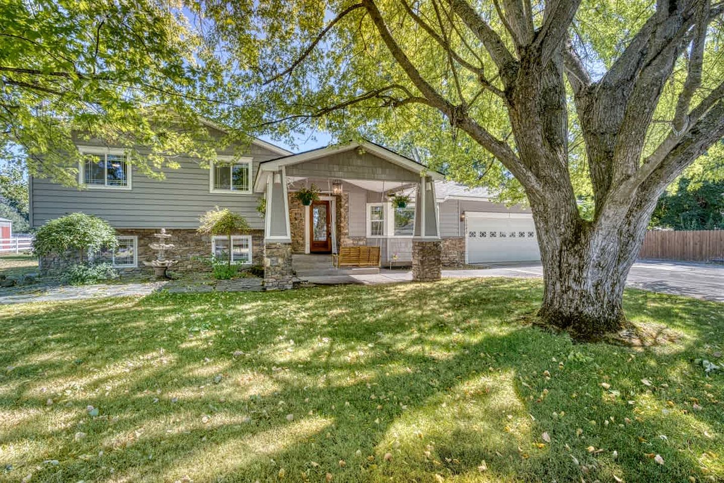A two-story house with a stone foundation, a front porch, and a garage.