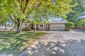 A residential house with a garage, a front yard, and a large tree providing shade. - Spacious 5BR Retreat with Hot Tub & Fire Pit Near Coeur d'Alene (Coeur d'Alene)