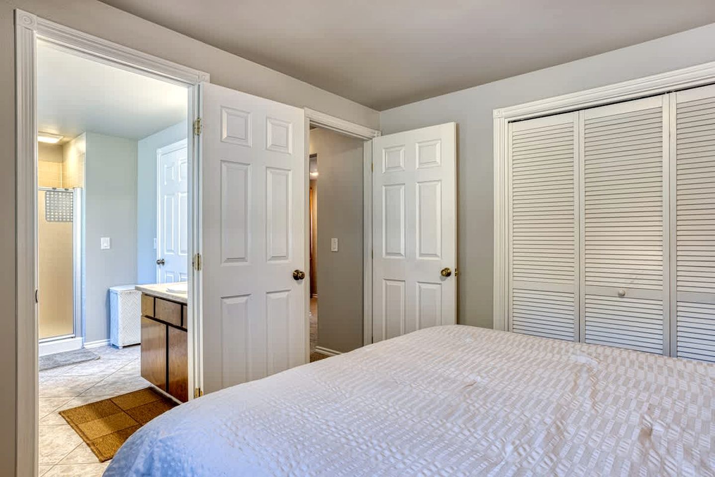 A bedroom with a bed, a walk-in closet, and a bathroom with a shower.