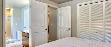 A bedroom with a bed, a walk-in closet, and a bathroom with a shower.