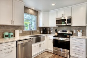 A modern kitchen with white cabinetry, stainless steel appliances, and a granite countertop. - Spacious 5BR Retreat with Hot Tub & Fire Pit Near Coeur d'Alene (Coeur d'Alene)