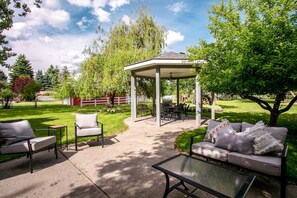 Un espace extérieur aménagé en terrasse, avec un gazebo, des sièges et une pelouse.