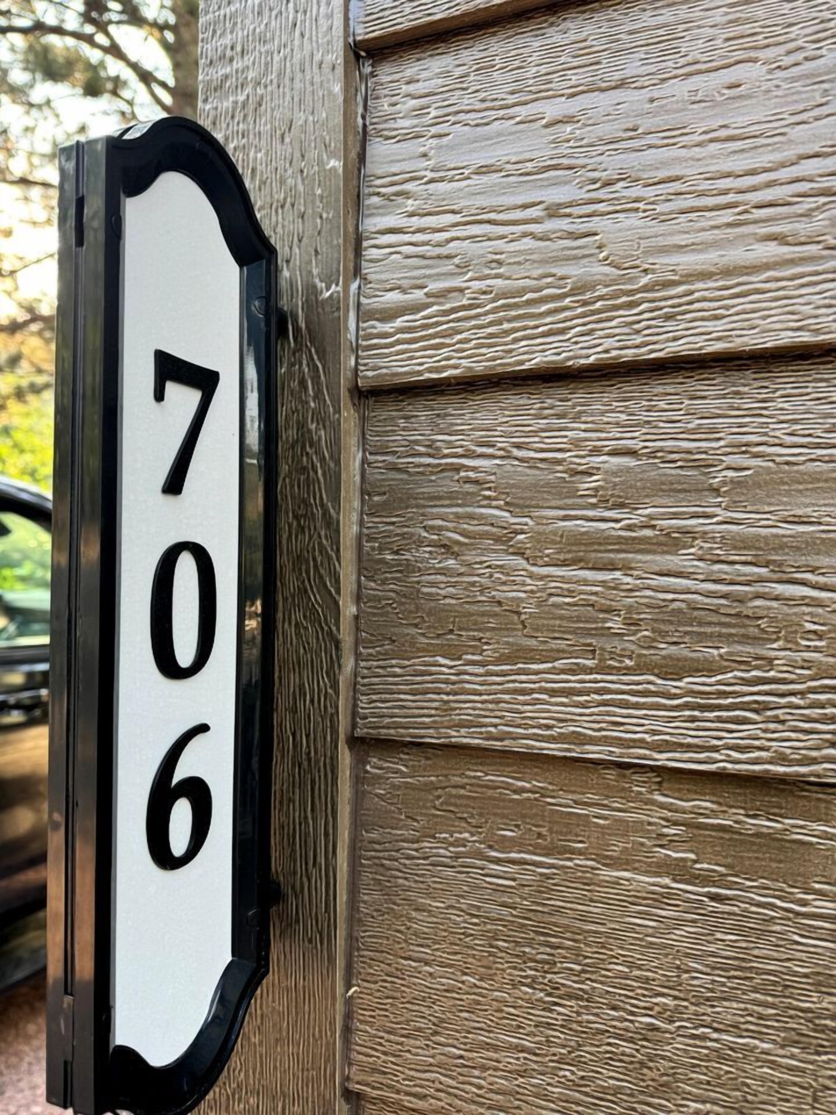 A house number sign with the number 706 mounted on a wooden post.
