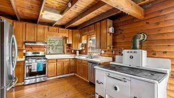 A kitchen with wooden walls, a stove, a sink, and a refrigerator.