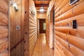 A wooden hallway with a door on the left and a window on the right.