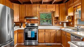 Una cocina con gabinetes de madera, un refrigerador de acero inoxidable, una estufa y un lavamanos.