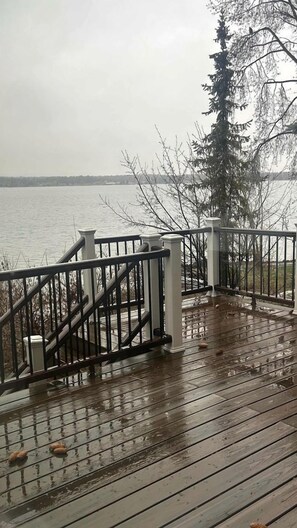 A wooden deck with a metal railing, overlooking a body of water. - Peaceful Waterfront Retreat with Fire Pit & Nature-Filled Surroundings in McCall, Idaho (McCall)