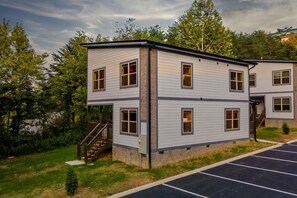 Monikerroksinen rakennus, jossa on tasakatto, portaat, jotka johtavat sisäänkäyntiin, ja merkityillä paikoilla varustettu pysäköintialue.