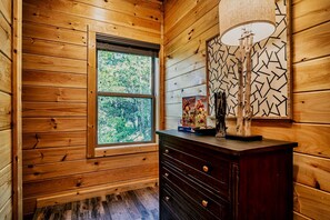 A wooden cabin interior with a window, a dresser, and a lamp. - Stylish Pigeon Forge Cabin with Hot Tub & Resort Amenities near Gatlinburg Golf Course, TN (Pigeon Forge)