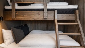 A bunk bed with a wooden ladder, white bedding, and black pillows.