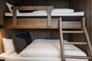 A bunk bed with a wooden ladder, white bedding, and black pillows.