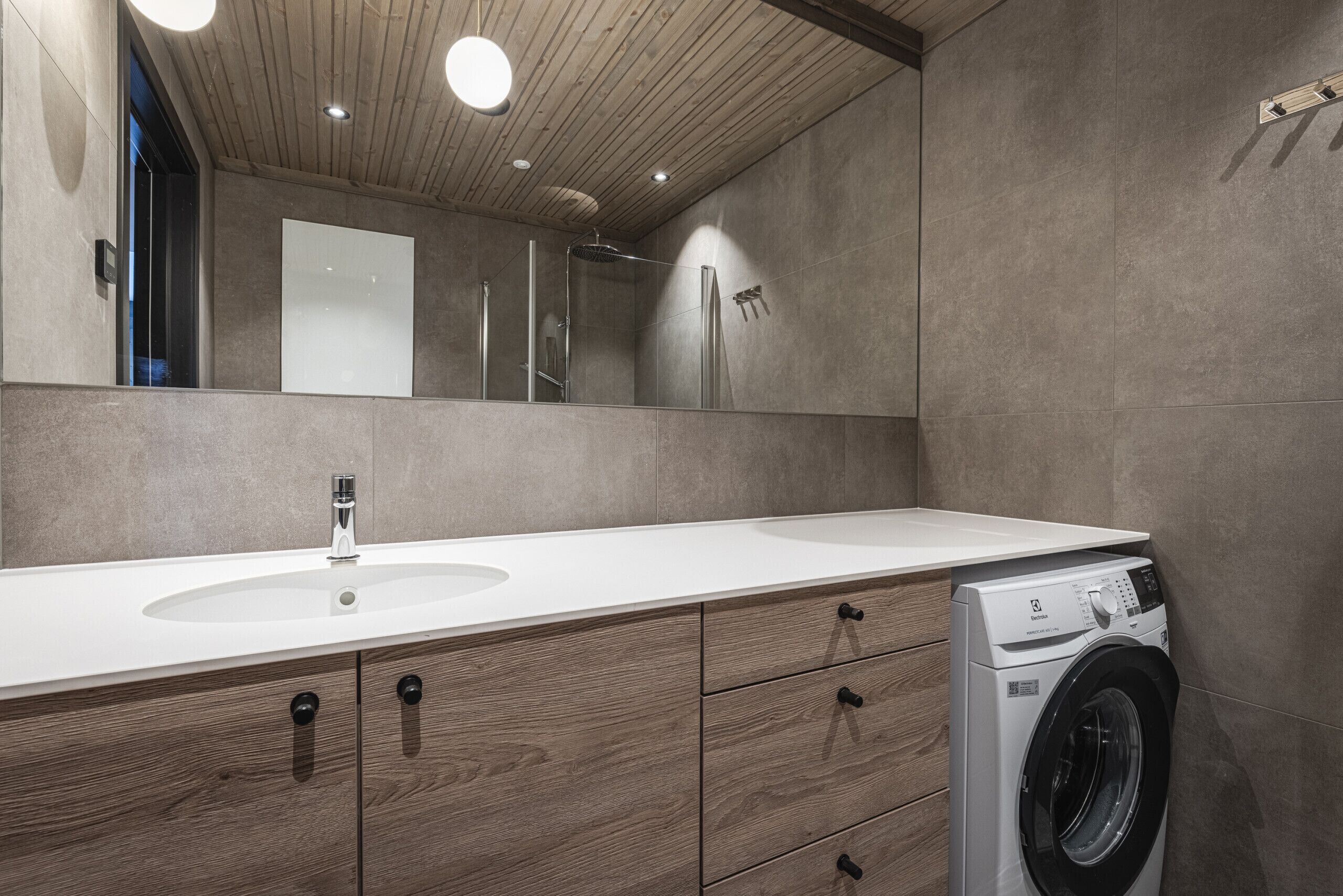 Ein modernes Badezimmer mit einem Holzbadezimmerhocker, einem Waschbecken, einem Spiegel und einer Waschmaschine.