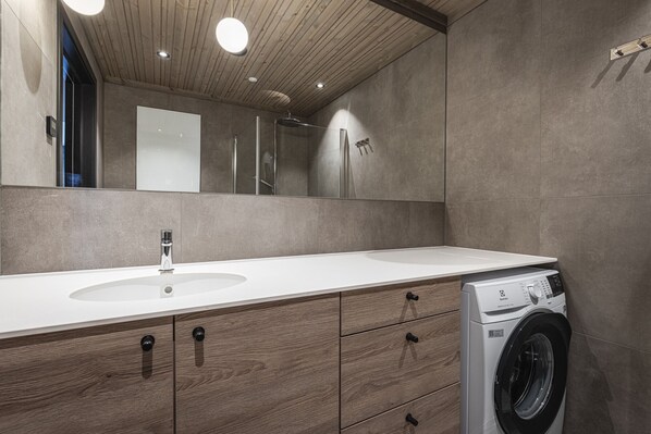 Une salle de bain moderne avec un meuble-lavabo en bois, un évier, un miroir et un lave-linge.