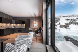 A modern interior with a kitchen, dining area, and a large window overlooking a snowy landscape.