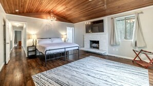 Une chambre avec un lit, une cheminée, un ventilateur de plafond et une vue sur l’extérieur.