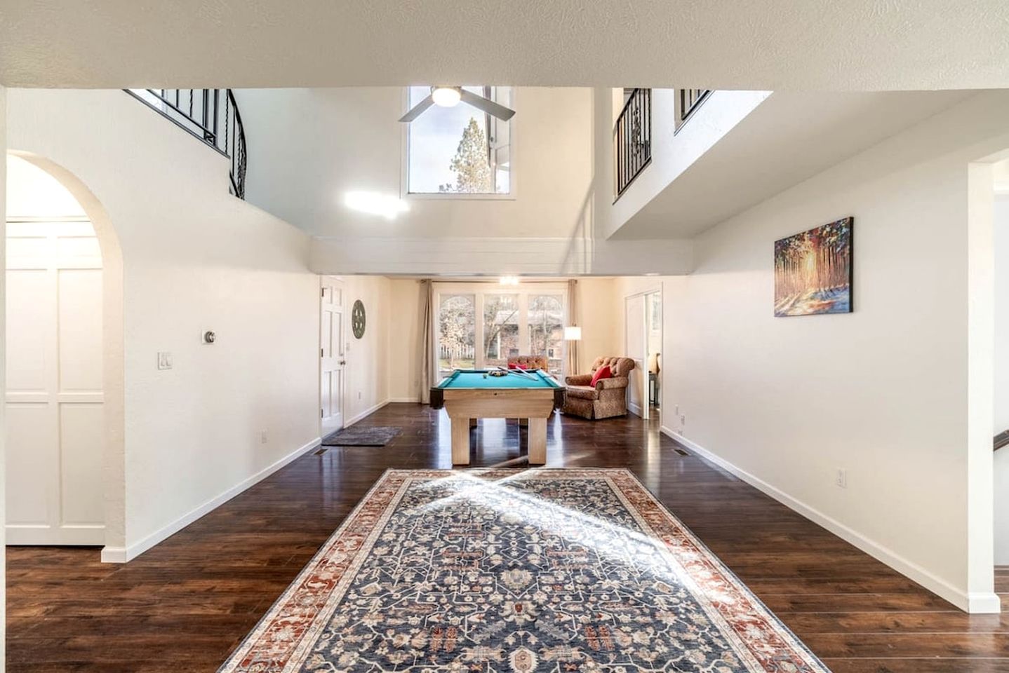 A spacious indoor area with a pool table, a rug, and a painting on the wall.