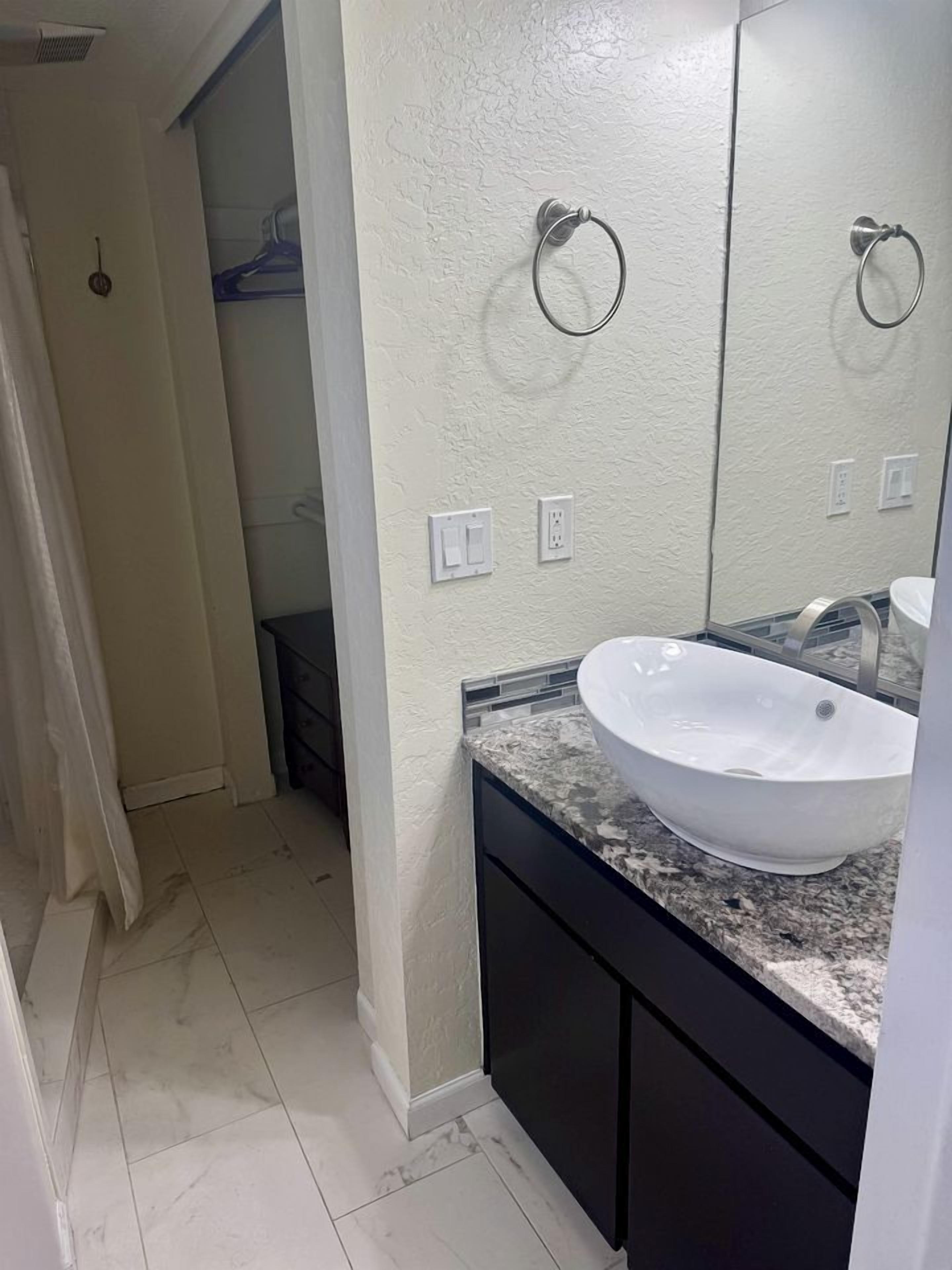 A bathroom with a white sink, dark cabinets, and a mirror.