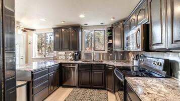 A modern kitchen with dark cabinetry, stainless steel appliances, and a granite countertop.