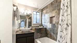 Une salle de bain avec une baignoire sur pieds, un lavabo sur colonne, un grand miroir et un espace douche.